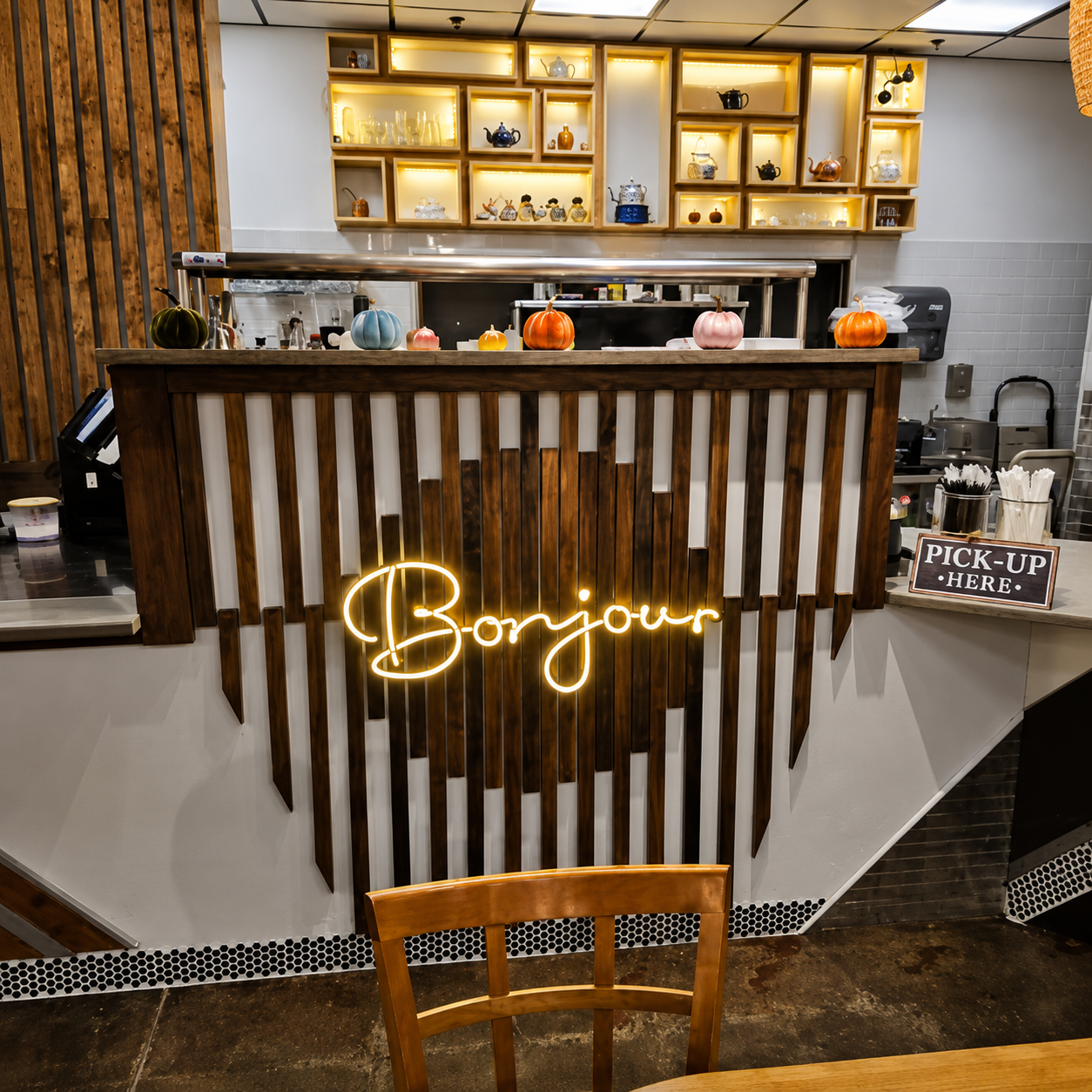 Front counter with warm wood paneling, softly lit display shelves, and a glowing Bonjour sign.